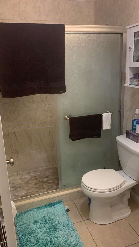 A bathroom featuring a tiled walk-in shower, a white toilet, and a teal bath mat — 1333 S Dixie Highway # 202, Deerfield Beach FL 33441, DEERFIELD BEACH, FL