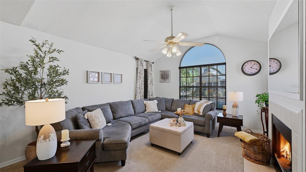 A living room features a gray sectional sofa, a fireplace, and a large arched window — 4504 CITATION LANE UNIT C, SARASOTA, FL
