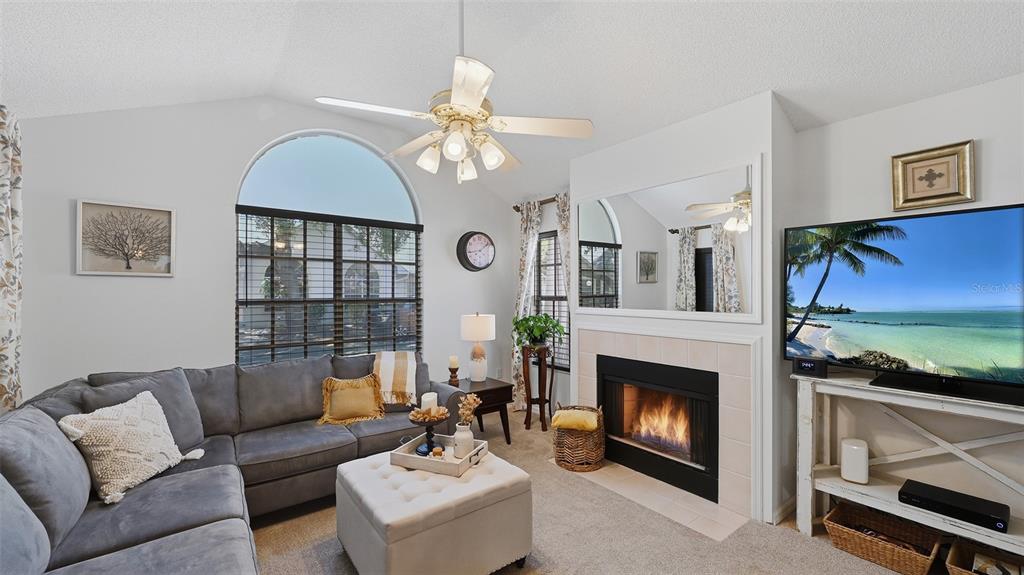 A living room features a grey sectional sofa, a fireplace, and a large arched window — 4504 CITATION LANE UNIT C, SARASOTA, FL