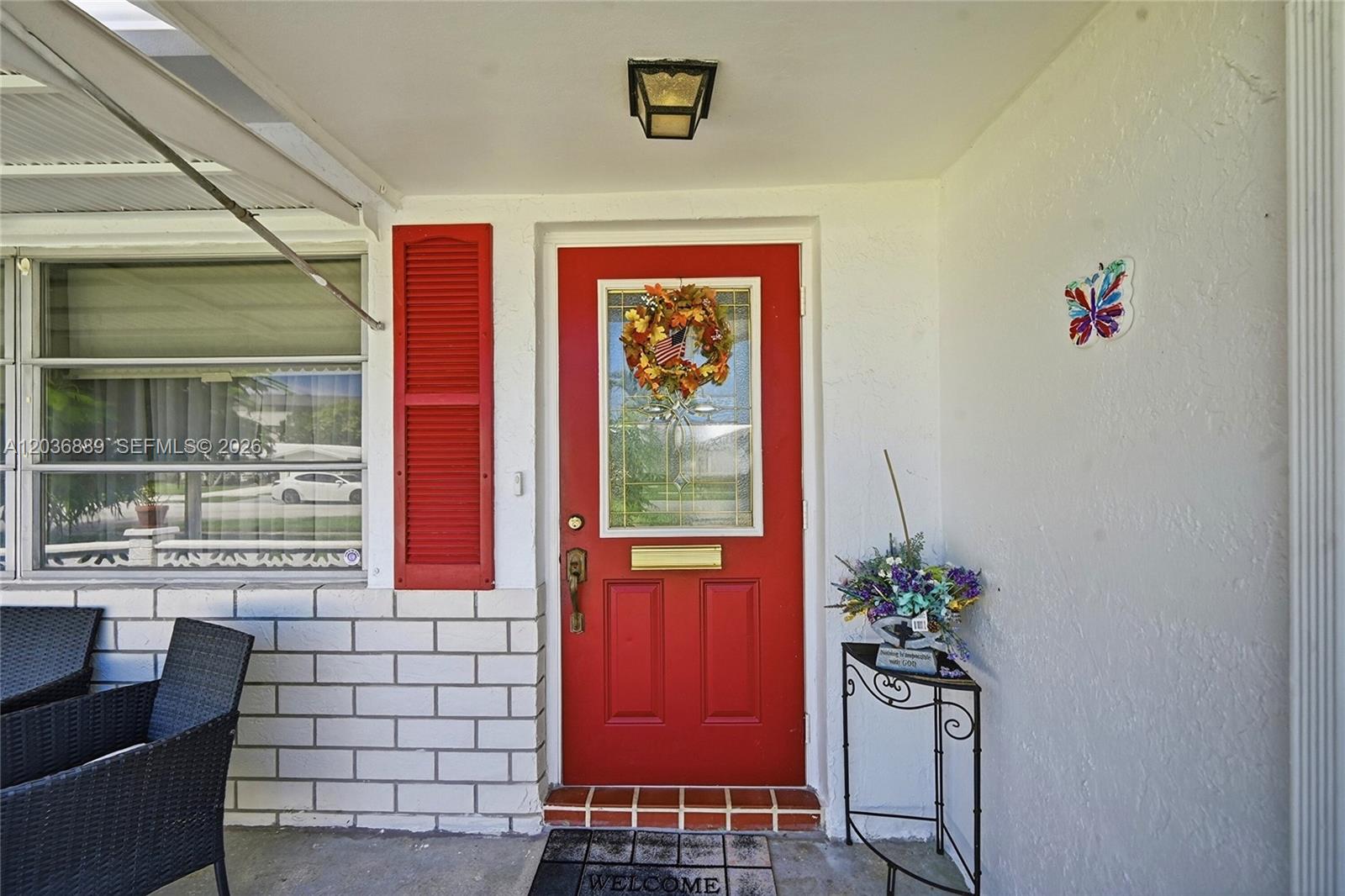 A red front door with a wreath and a welcome mat on a covered porch — 1702 SW 22nd St, Boynton Beach FL 33426, BOYNTON BEACH, FL
