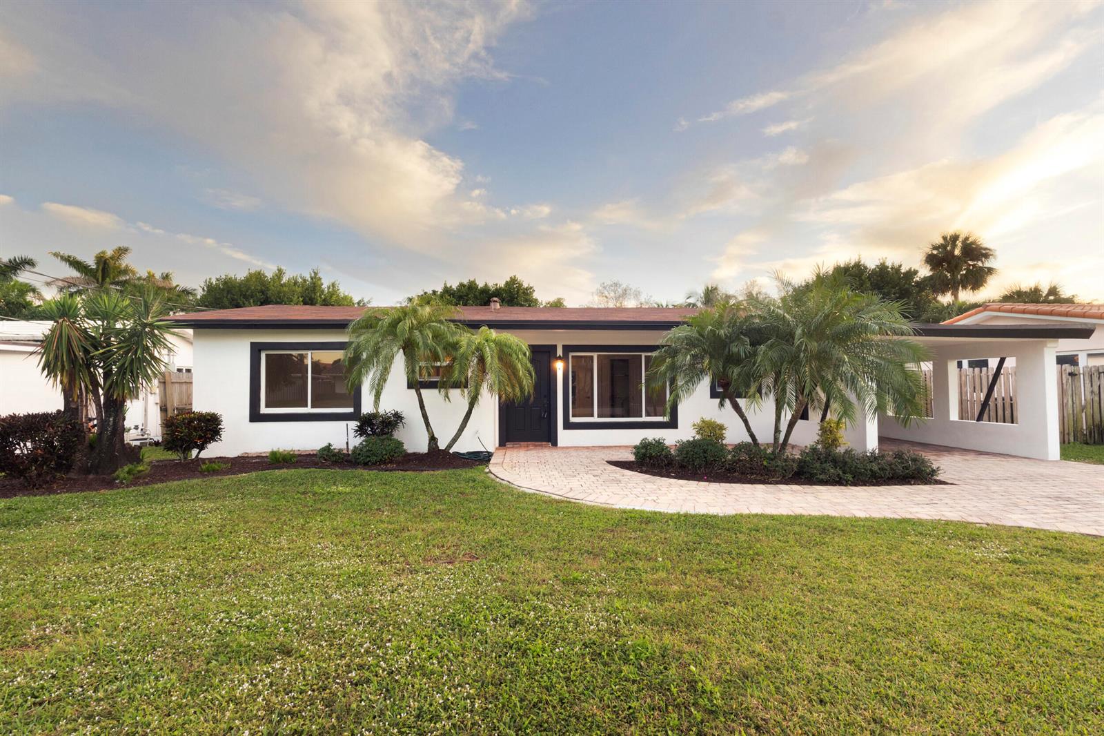 A single-story white house with a dark roof, black window trim, and a paved driveway — 2940 NE 18th Street, Pompano Beach FL 33062, POMPANO BEACH, FL