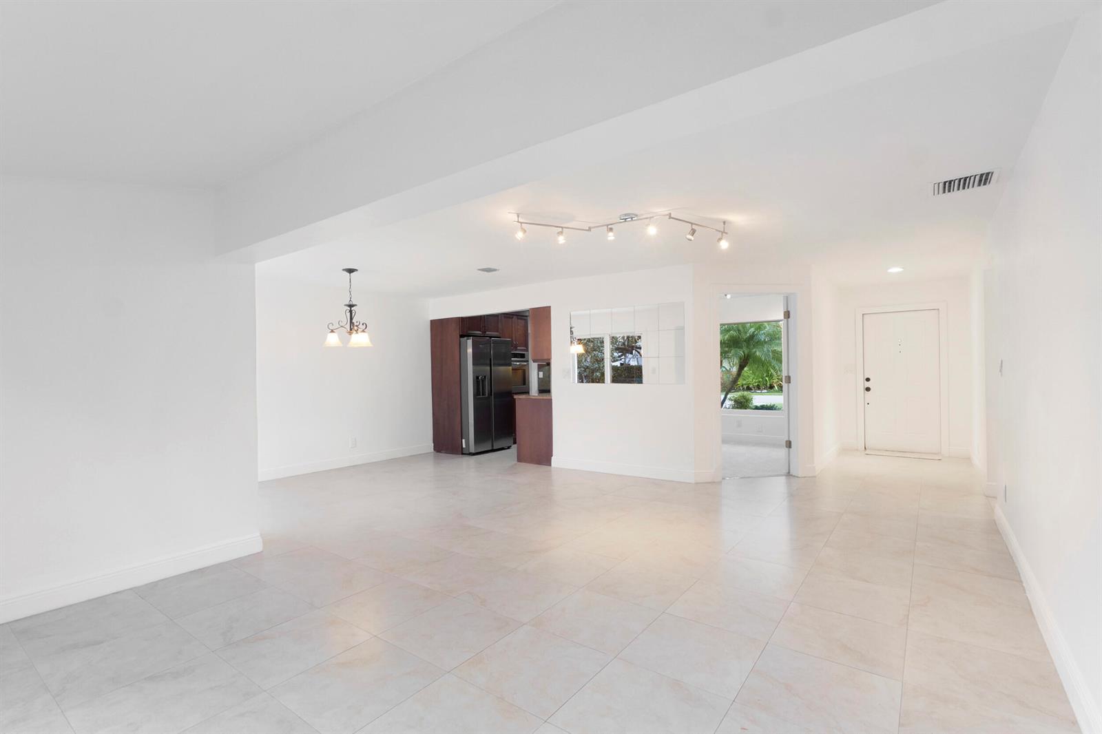 An open-concept living area features white walls, light tile flooring, and a dark wood kitchen — 2940 NE 18th Street, Pompano Beach FL 33062, POMPANO BEACH, FL