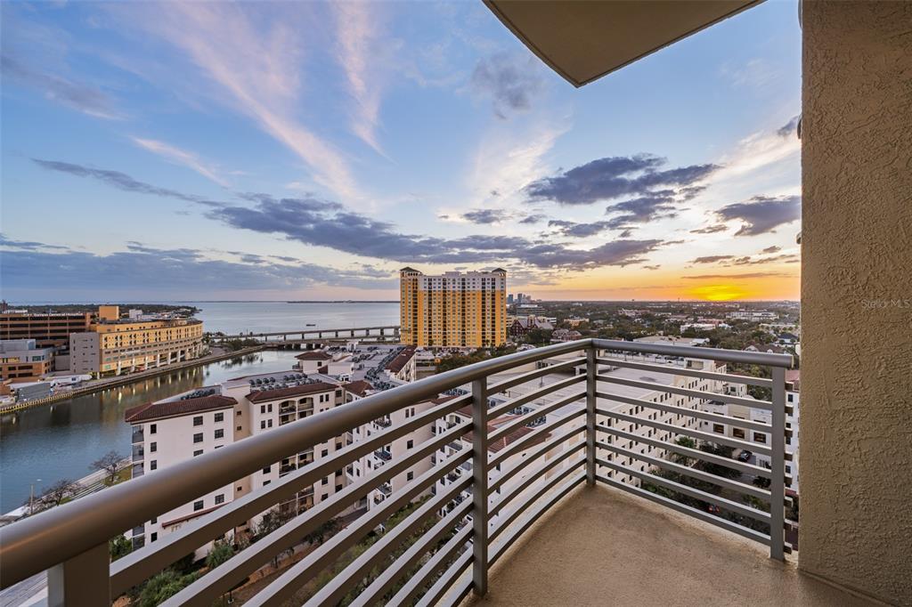 A balcony with metal railings overlooks a city skyline, a river, and a sunset — 275 BAYSHORE BOULEVARD UNIT 1507, TAMPA, FL