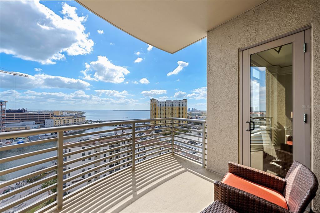 A balcony with a metal railing overlooks a waterfront cityscape under a blue sky — 275 BAYSHORE BOULEVARD UNIT 1507, TAMPA, FL