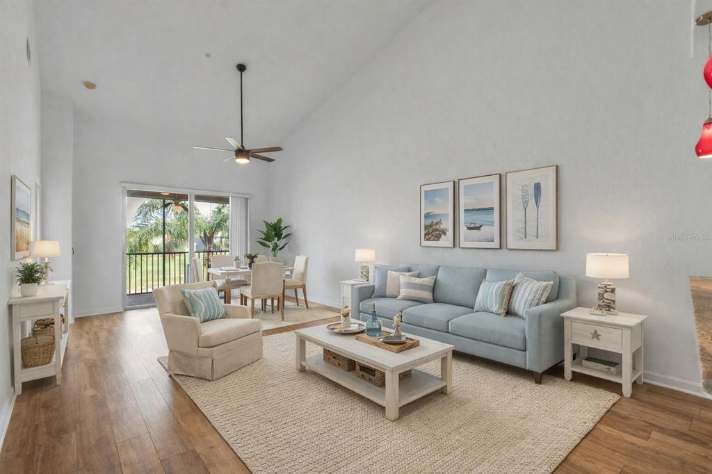 A living room with light blue sofa, beige armchair, coffee table, and wood-look flooring — 819 FAIRWAYCOVE LANE UNIT 203, BRADENTON, FL