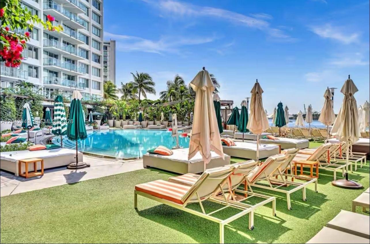 A swimming pool surrounded by lounge chairs and umbrellas on a grassy deck — 1100 West Ave # 1007, Miami Beach FL 33139, MIAMI BEACH, FL