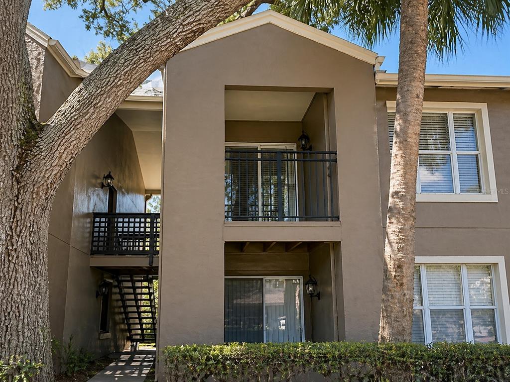 Exterior view of a two-story apartment building with balconies, stairs, and large trees — 607 S WESTLAND AVENUE UNIT 19, TAMPA, FL