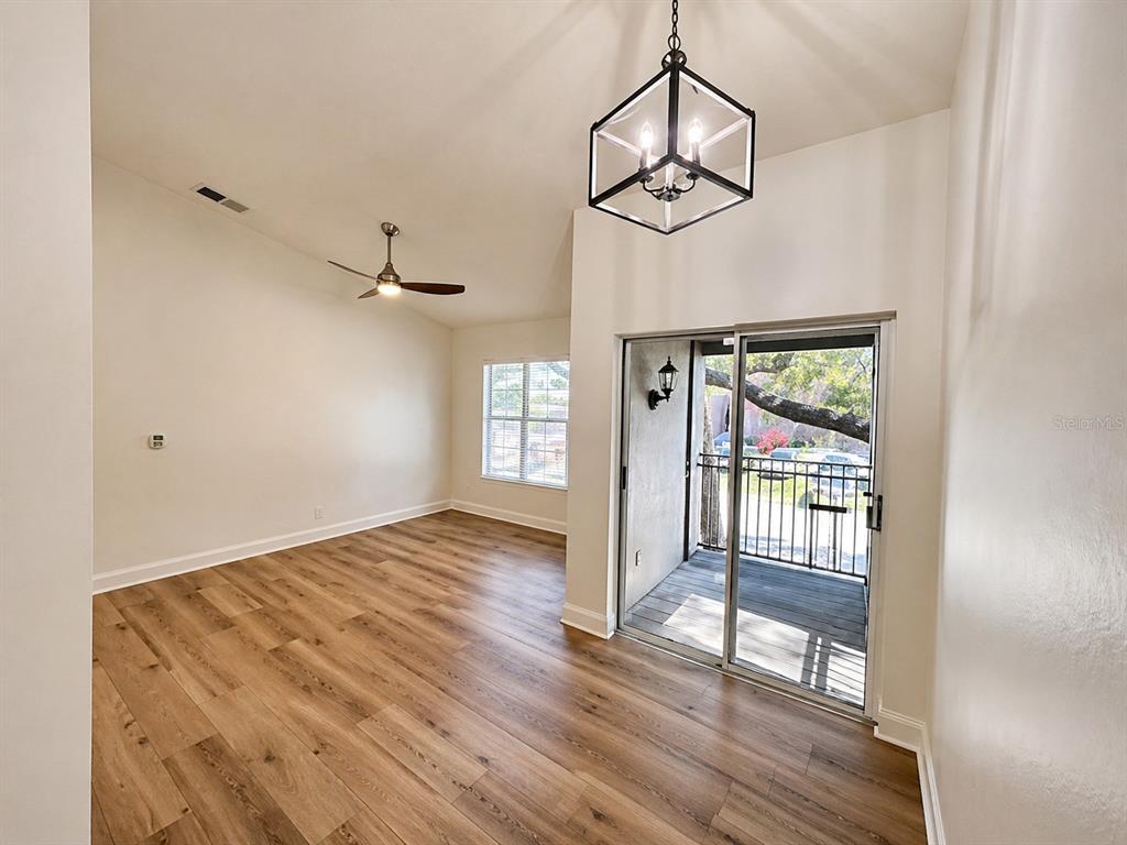 A room with wood-look flooring, a vaulted ceiling, a ceiling fan, and a sliding glass door — 607 S WESTLAND AVENUE UNIT 19, TAMPA, FL