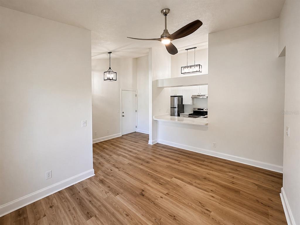 An open-concept living area features wood-look flooring, a ceiling fan, and an adjacent kitchen — 607 S WESTLAND AVENUE UNIT 19, TAMPA, FL