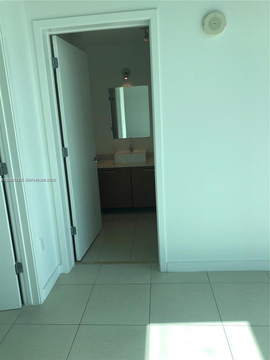 A view through an open doorway into a bathroom with a vanity and mirror — 3301 NE 1 AVE # H1003, Miami FL 33137, MIAMI, FL