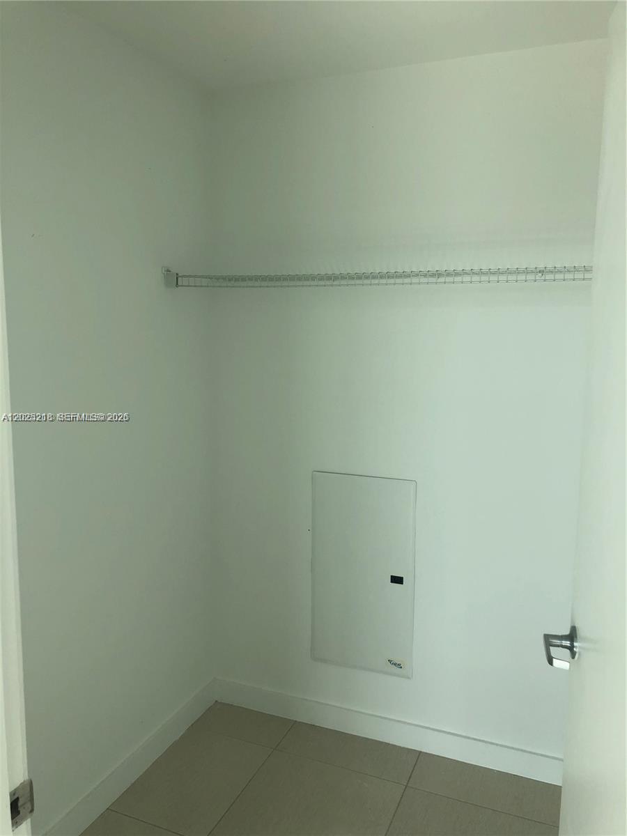 A small closet features white walls, tile flooring, a wire shelf, and an electrical panel — 3301 NE 1 AVE # H1003, Miami FL 33137, MIAMI, FL