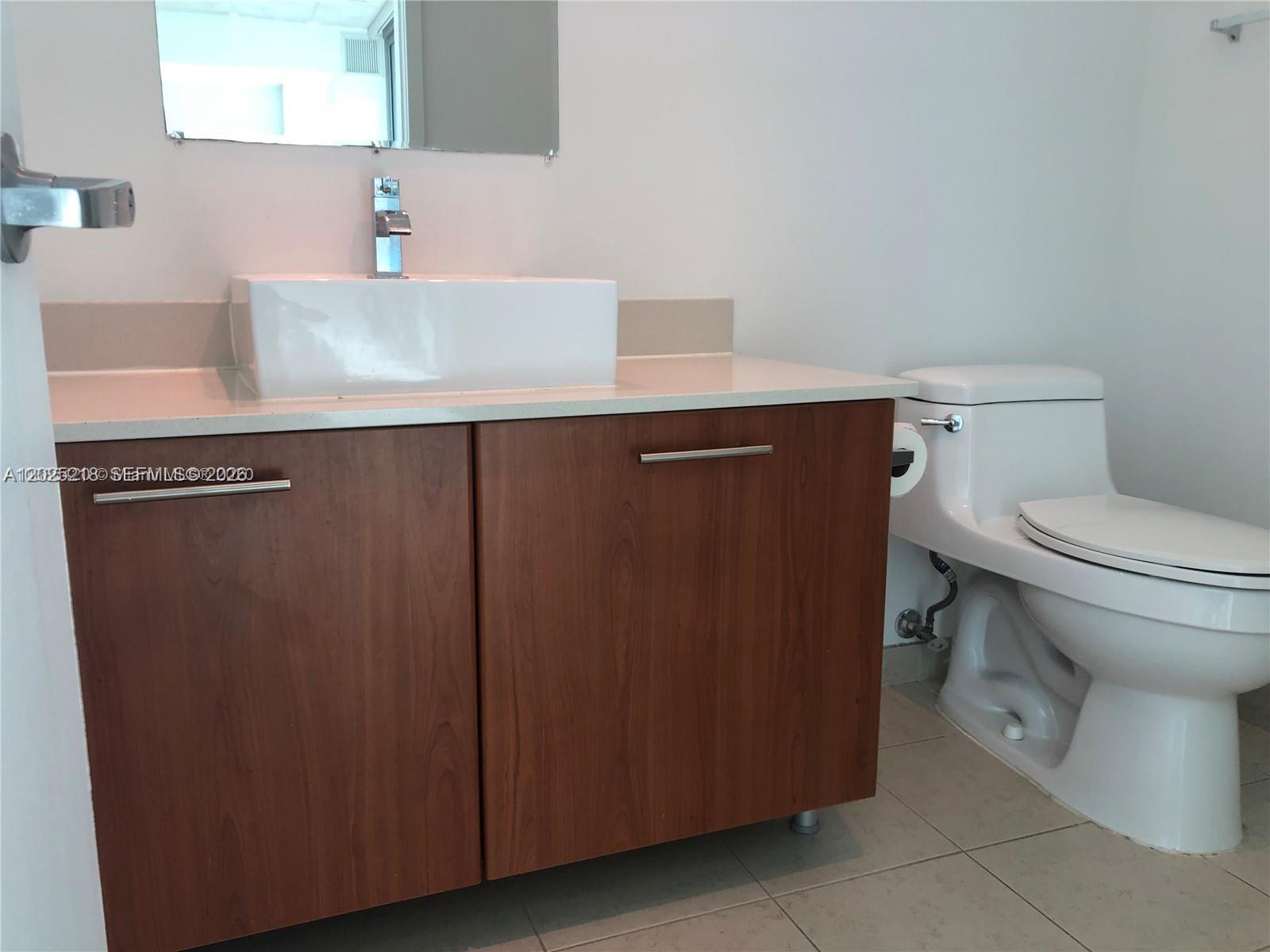A bathroom features a white vessel sink on a wood vanity next to a toilet — 3301 NE 1 AVE # H1003, Miami FL 33137, MIAMI, FL