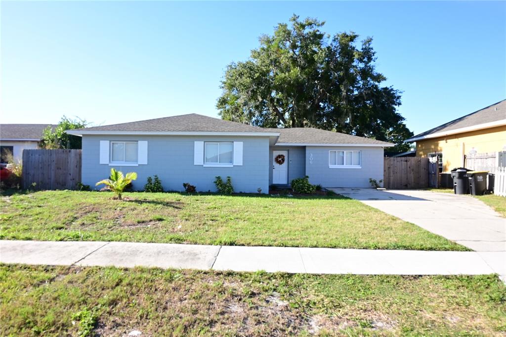 A single-story gray house with white shutters and a concrete driveway sits on a lawn — 306 FERN ROAD, WINTER HAVEN, FL