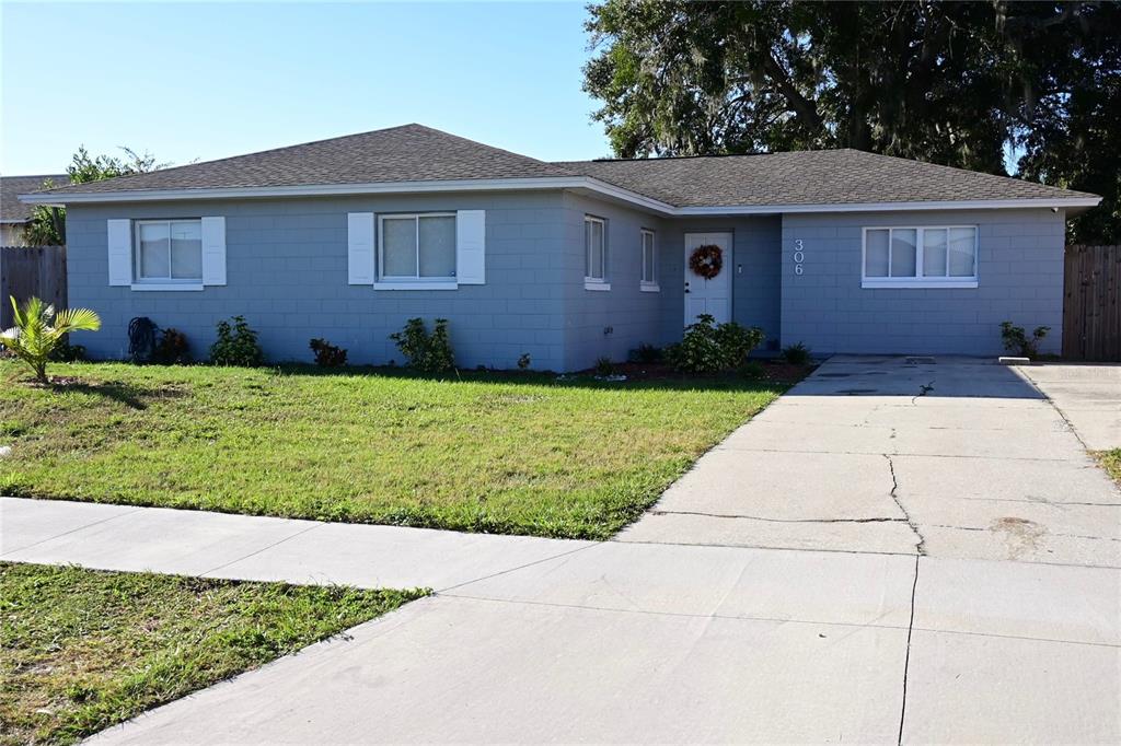 A single-story gray concrete block house with a shingled roof and a concrete driveway — 306 FERN ROAD, WINTER HAVEN, FL