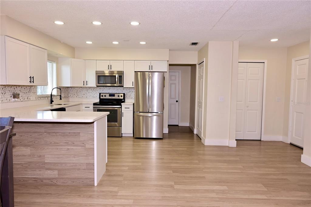 A kitchen features white cabinets, stainless steel appliances, a breakfast bar, and light wood flooring — 306 FERN ROAD, WINTER HAVEN, FL