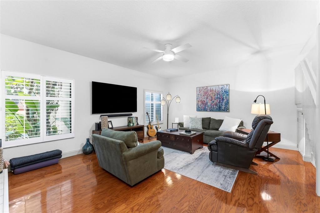 A living room features hardwood floors, a ceiling fan, a television, and a seating area — 3460 COUNTRYSIDE BOULEVARD UNIT 66, CLEARWATER, FL