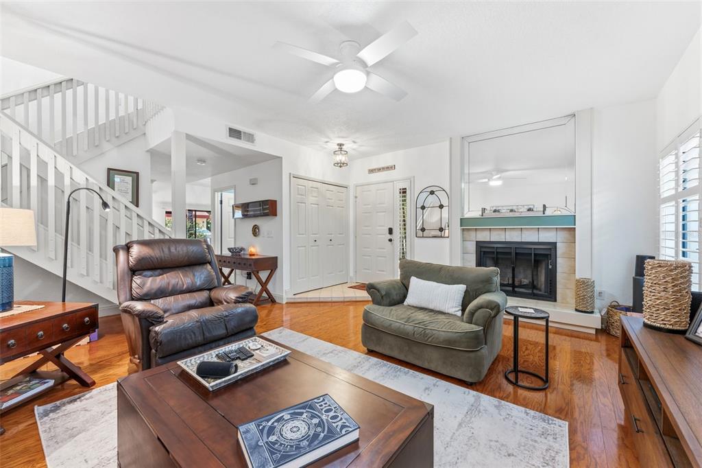 A living room features a fireplace, a ceiling fan, a staircase, and hardwood flooring — 3460 COUNTRYSIDE BOULEVARD UNIT 66, CLEARWATER, FL