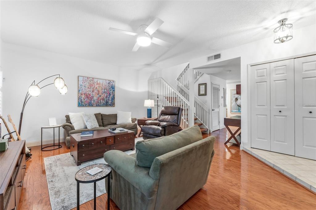 A living room features hardwood floors, a sofa, a recliner, and a staircase — 3460 COUNTRYSIDE BOULEVARD UNIT 66, CLEARWATER, FL