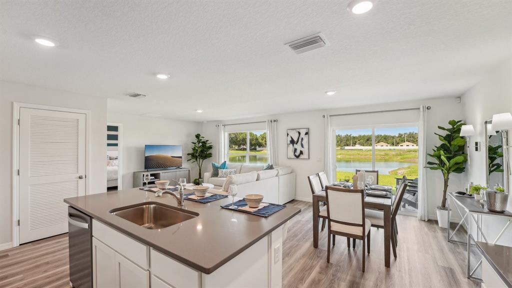 A kitchen island with a sink overlooks an open-concept living and dining area with water views — 5736 SW 130TH LANE, OCALA, FL