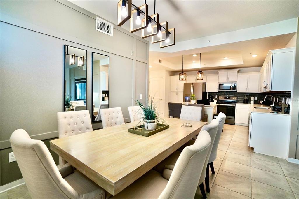 A dining area with a wooden table and upholstered chairs sits adjacent to a kitchen — 4741 CLOCK TOWER DRIVE UNIT 108, KISSIMMEE, FL