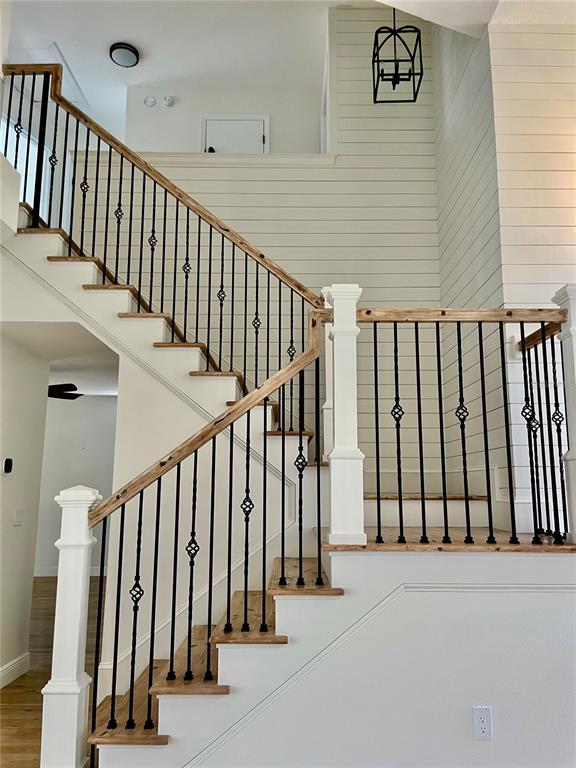 A staircase with wooden treads and black metal balusters ascends against a shiplap wall — 13261 ROYAL GEORGE AVENUE, ODESSA, FL