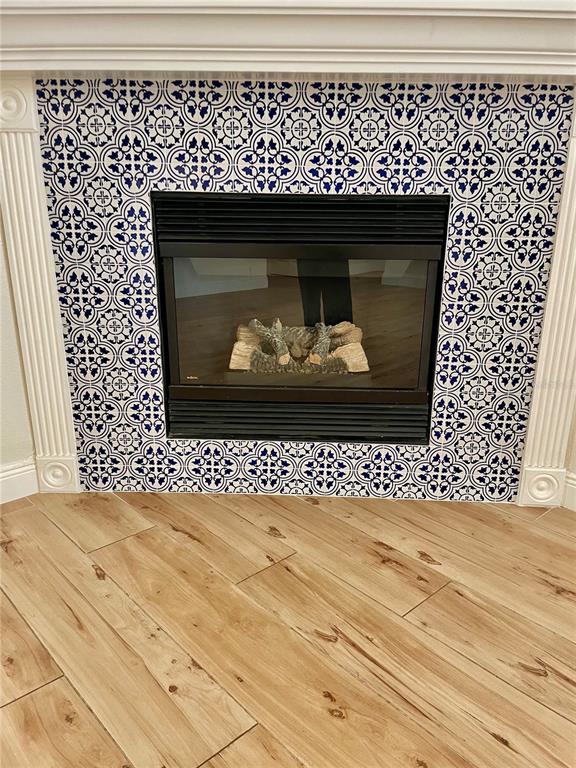 A fireplace with blue and white patterned tiles is centered on a light wood floor — 13261 ROYAL GEORGE AVENUE, ODESSA, FL