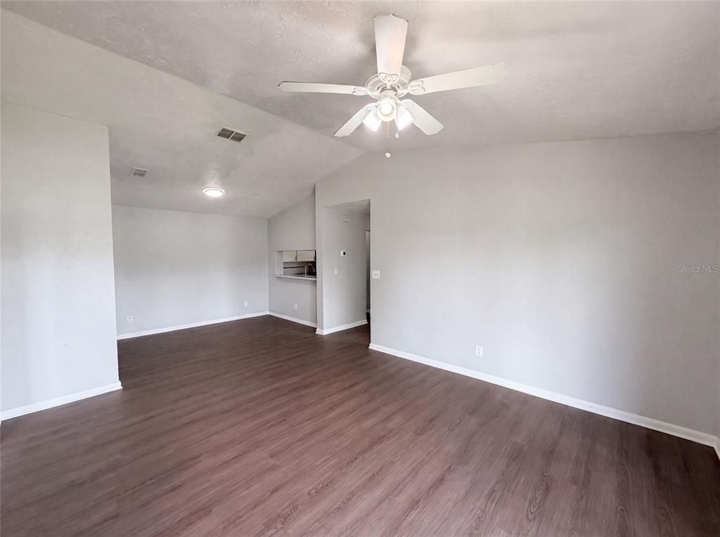 An empty living room features gray walls, dark wood-look flooring, and a ceiling fan — 5213 VIA HACIENDA CIRCLE UNIT 307, ORLANDO, FL