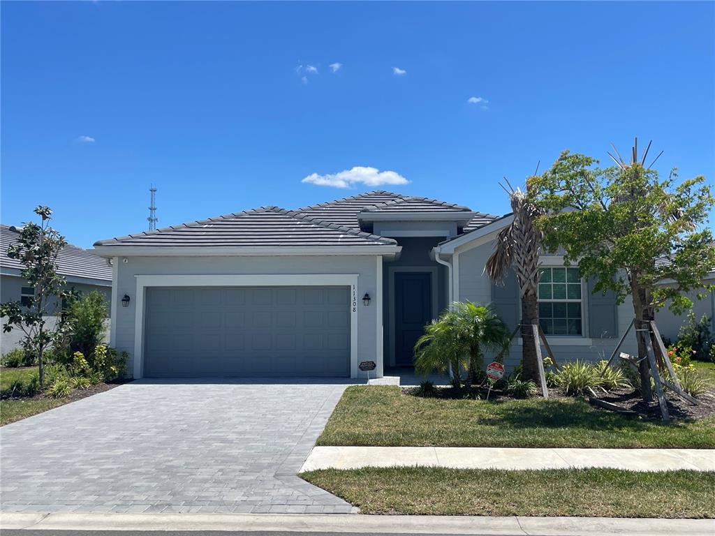 A single-story house with a gray garage, tiled roof, and a paved driveway — 11308 PINOT DRIVE, VENICE, FL