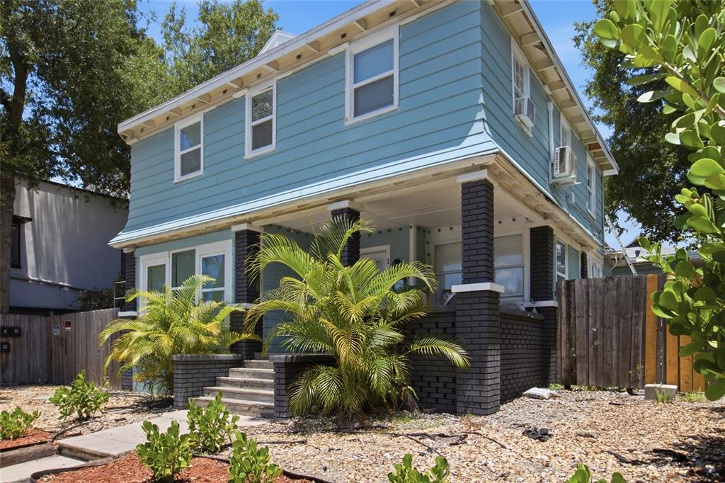 A two-story blue house with dark brick porch columns and a gravel front yard — 335 5TH AVENUE N, ST PETERSBURG, FL