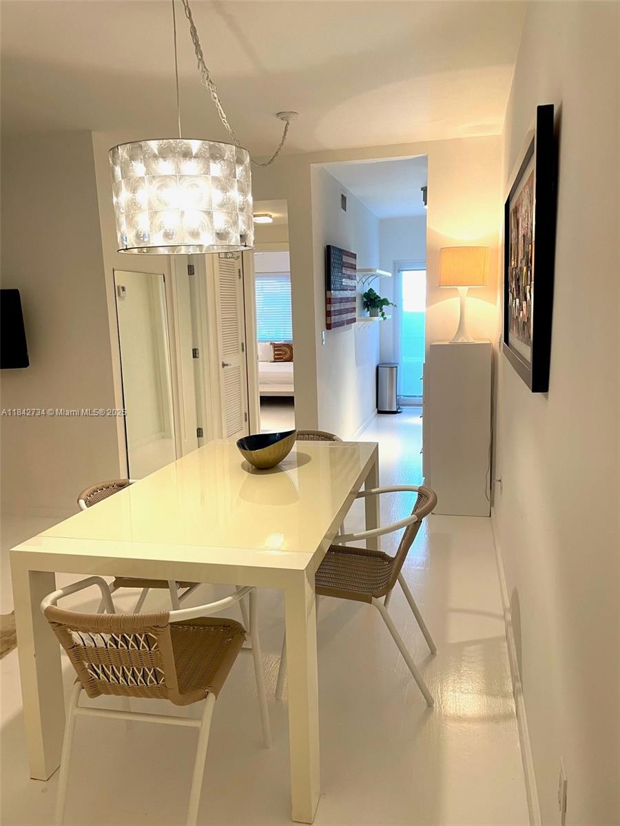 A dining area features a white table, woven chairs, and a modern pendant light fixture — 1616 Euclid Ave # 14, Miami Beach FL 33139, MIAMI BEACH, FL