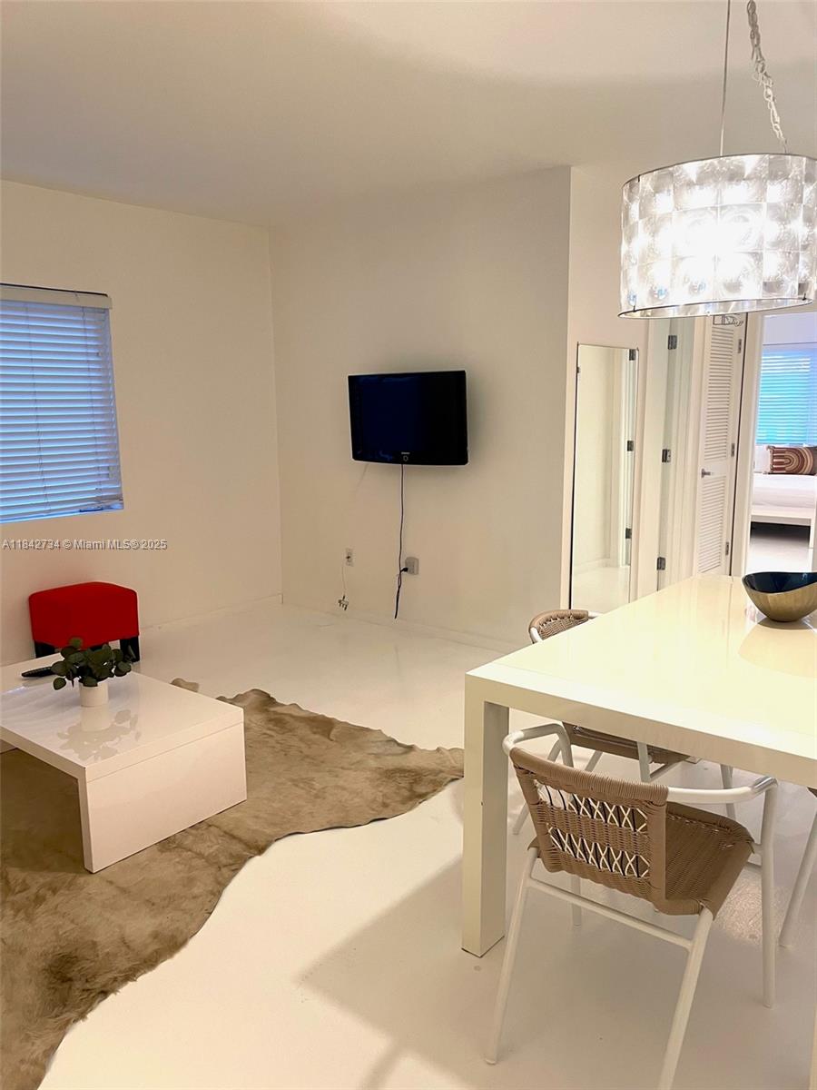 A bright living and dining area features white floors, a wall-mounted television, and modern furniture — 1616 Euclid Ave # 14, Miami Beach FL 33139, MIAMI BEACH, FL