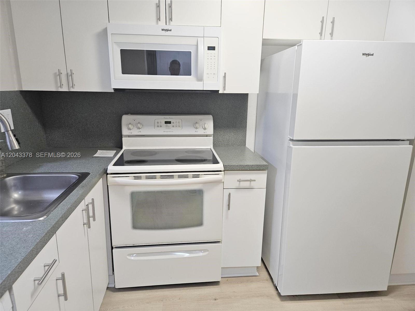 A kitchen features white cabinets, white appliances, and gray countertops — 11223 SW 88th St # 216C, Miami FL 33176, MIAMI, FL