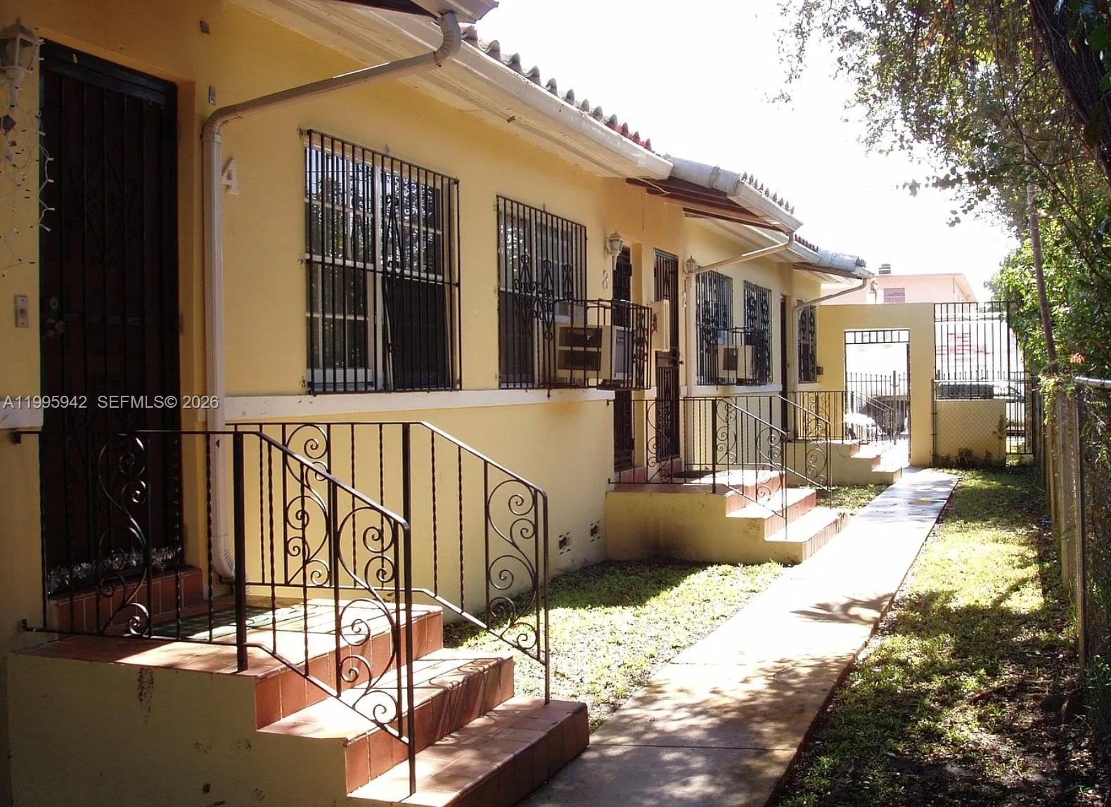 A row of yellow residential units with metal security bars and exterior staircases — 1325 SW 6th St, Miami FL 33135, MIAMI, FL