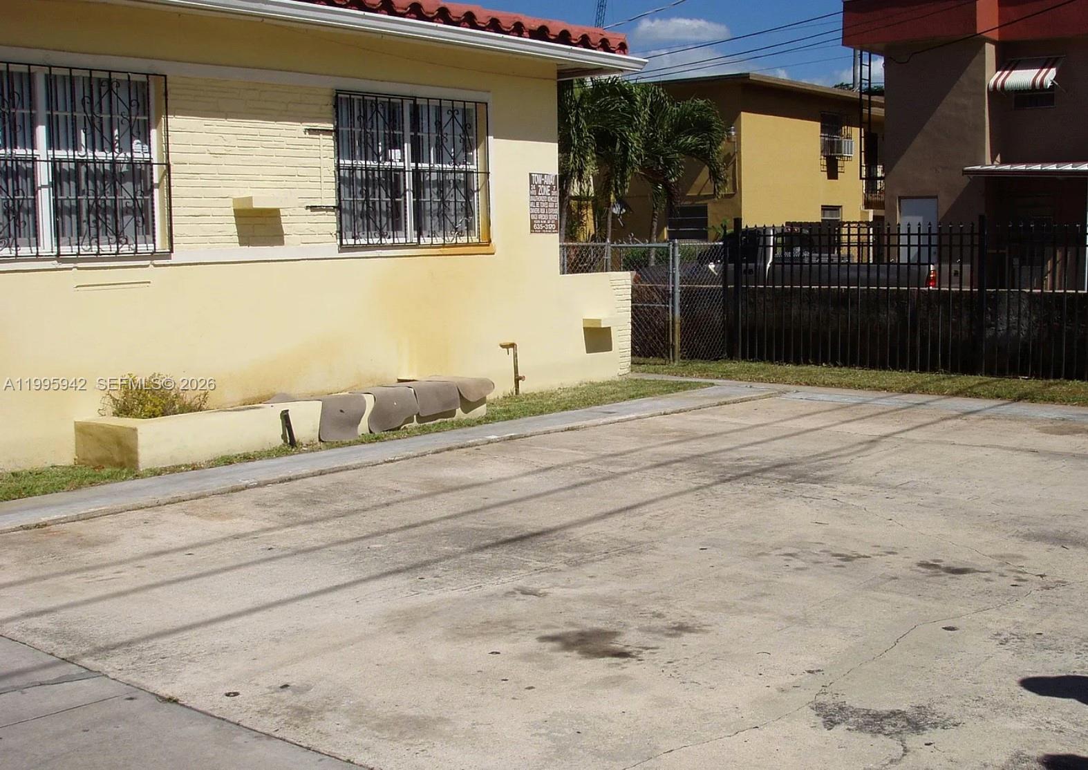 A paved parking area sits beside a yellow building with security bars on the windows — 1325 SW 6th St, Miami FL 33135, MIAMI, FL