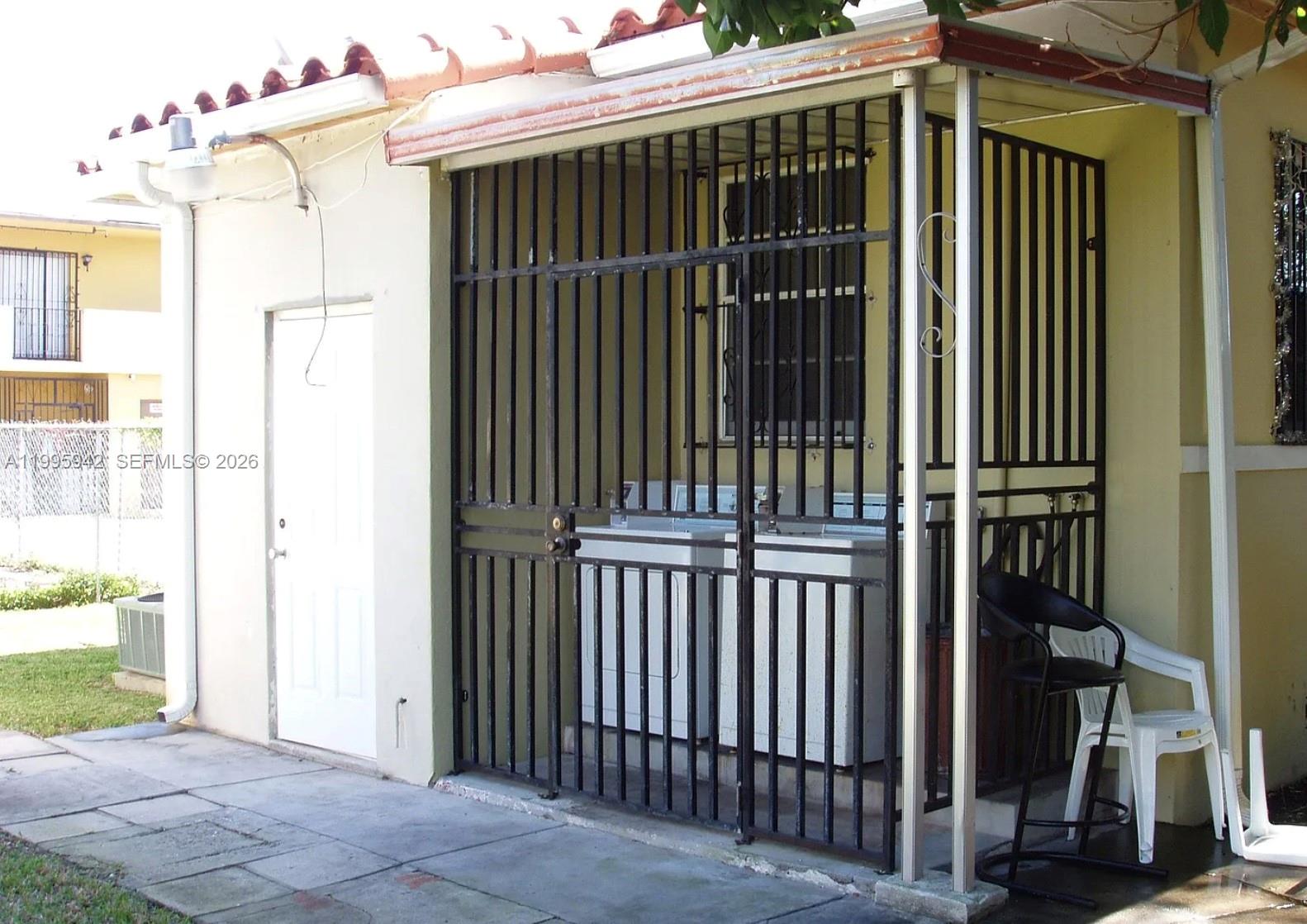 A laundry area with a washer and dryer is enclosed by a black metal gate — 1325 SW 6th St, Miami FL 33135, MIAMI, FL