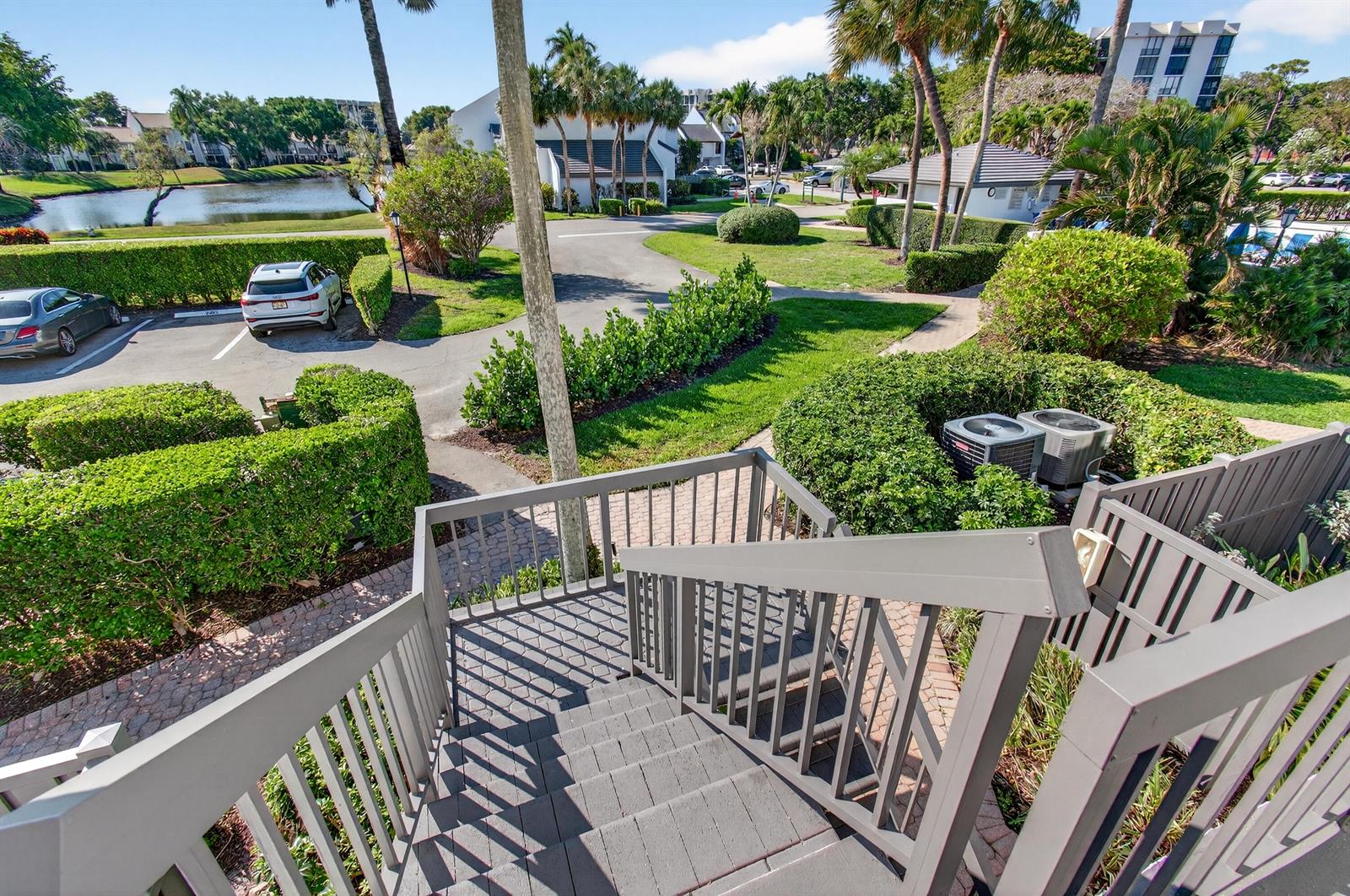 An elevated view from a wooden staircase looking out over a parking lot and pond — 2303 Bridgewood Drive # 2303, Boca Raton FL 33434, BOCA RATON, FL