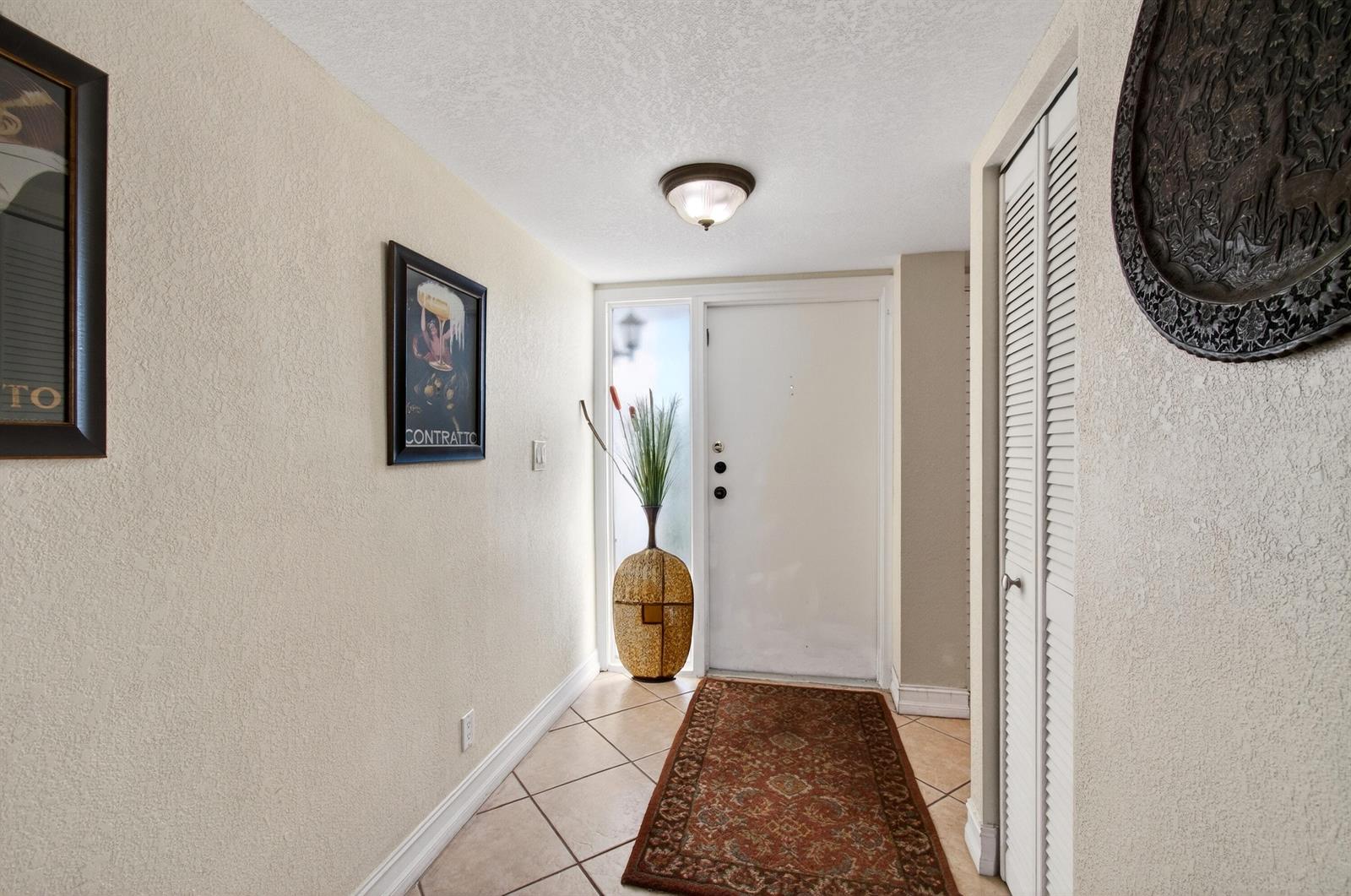 A tiled entryway features a white front door, a decorative vase, and framed wall art — 2303 Bridgewood Drive # 2303, Boca Raton FL 33434, BOCA RATON, FL