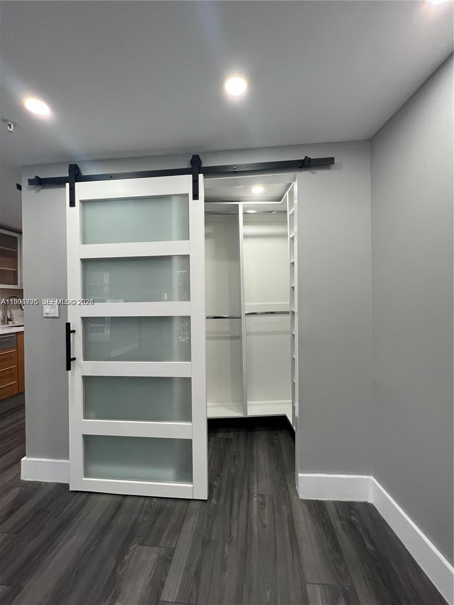 A sliding barn door with frosted glass panels opens into a white walk-in closet — 1750 N Bayshore Dr # 1507, Miami FL 33132, MIAMI, FL