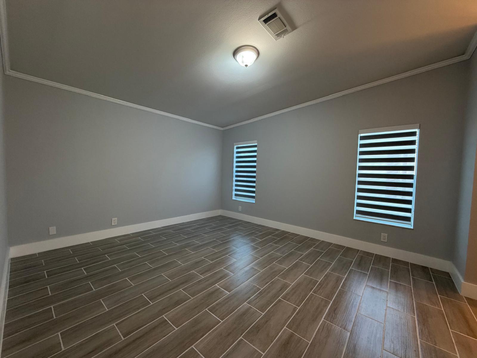 An empty room with gray walls, white crown molding, and wood-look tile flooring — 4165 3rd Court, Atlantis FL 33462, ATLANTIS, FL
