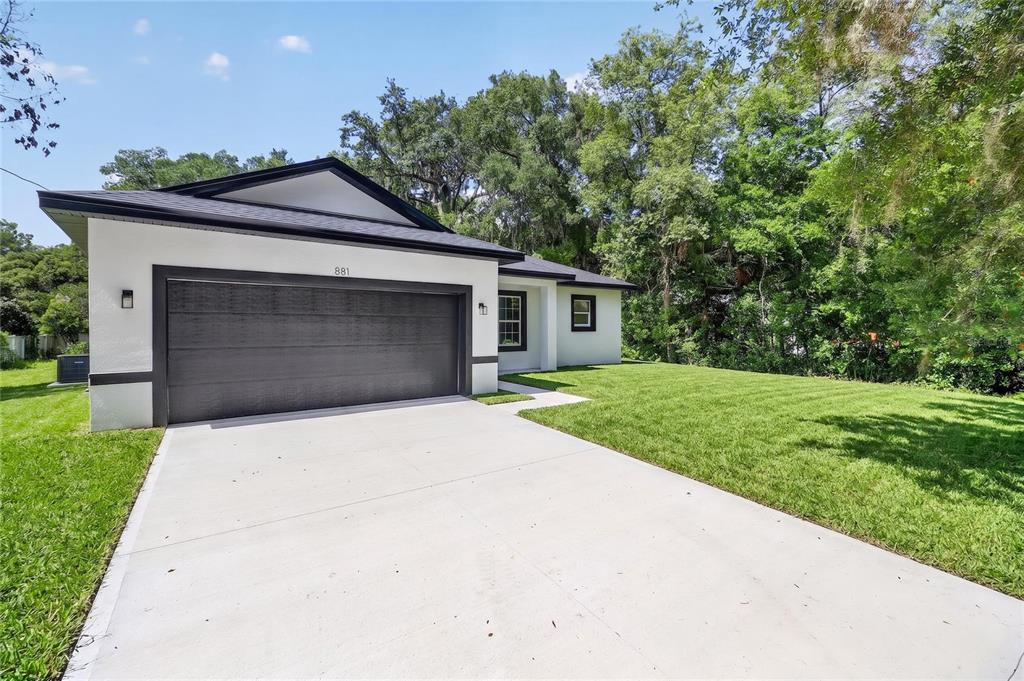 A modern white house with a dark roof and a two-car garage — 881 W WISCONSIN AVENUE, ORANGE CITY, FL