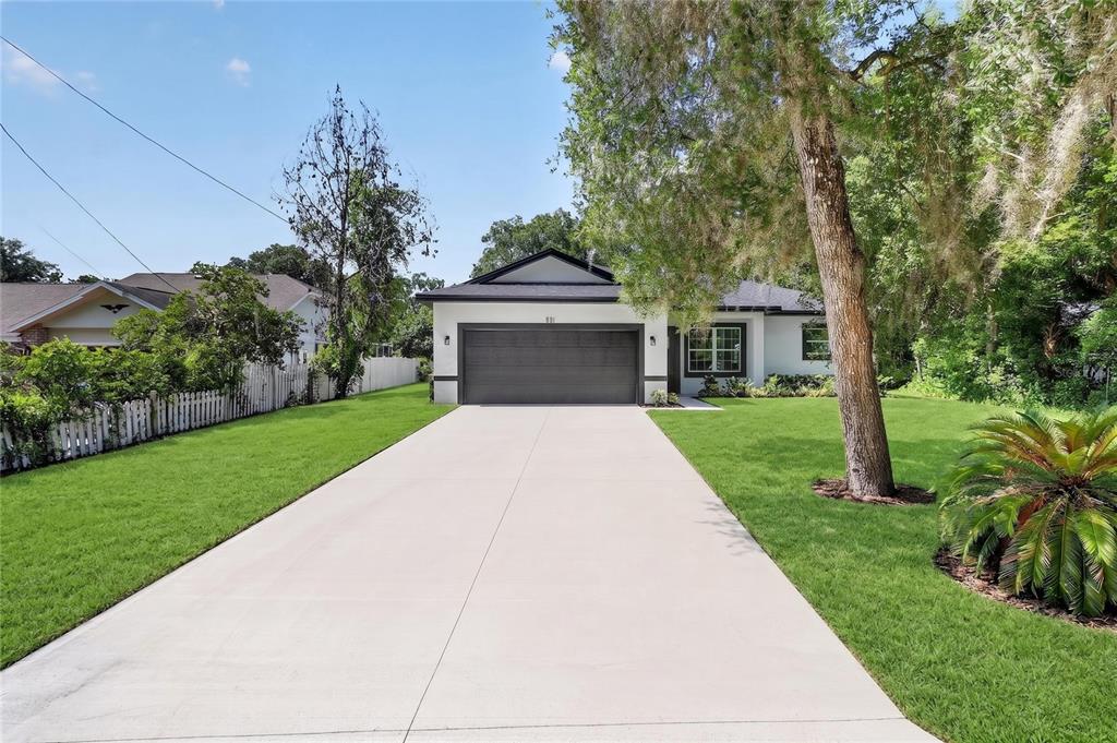A single-story house with a white exterior, dark roof, and a large concrete driveway — 881 W WISCONSIN AVENUE, ORANGE CITY, FL