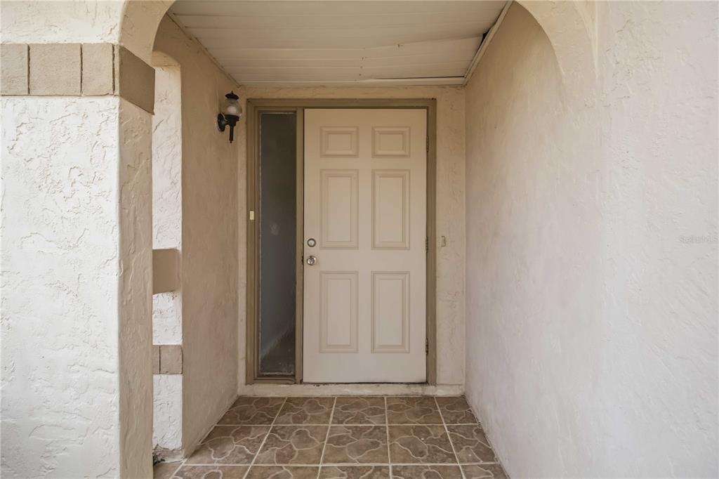A beige front door with a side window sits under a covered entryway — 4108 ABBOTSFORD STREET, NORTH PORT, FL