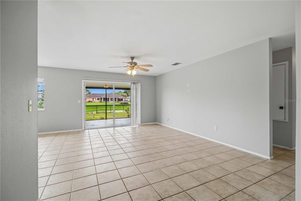 A spacious room with light gray walls, beige tile flooring, a ceiling fan, and sliding doors — 4108 ABBOTSFORD STREET, NORTH PORT, FL
