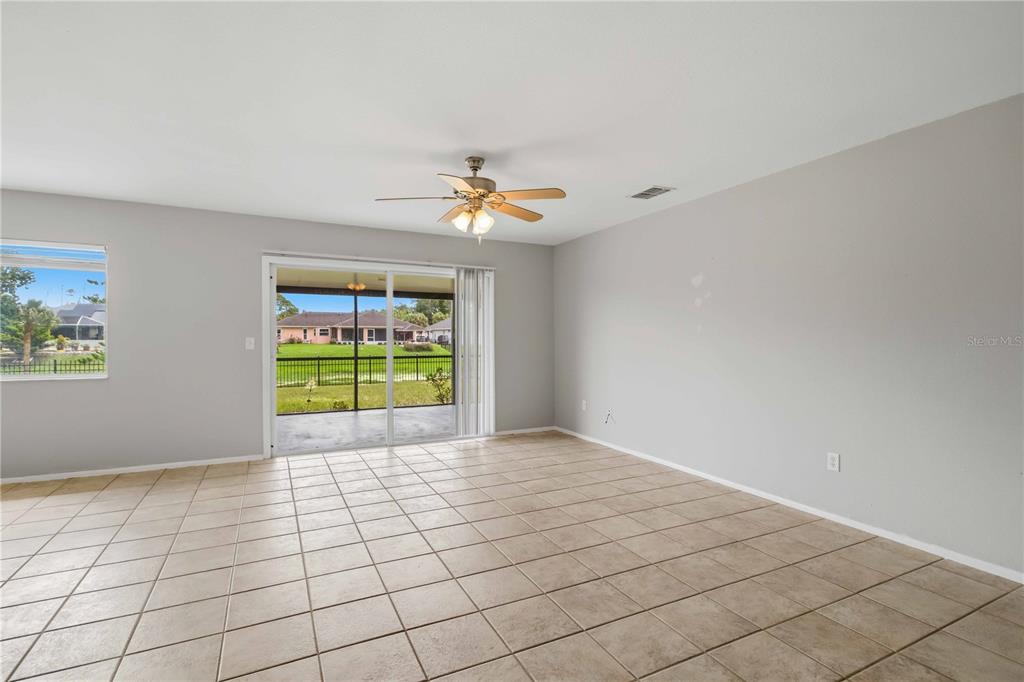 A living room features light tile flooring, gray walls, a ceiling fan, and sliding glass doors — 4108 ABBOTSFORD STREET, NORTH PORT, FL