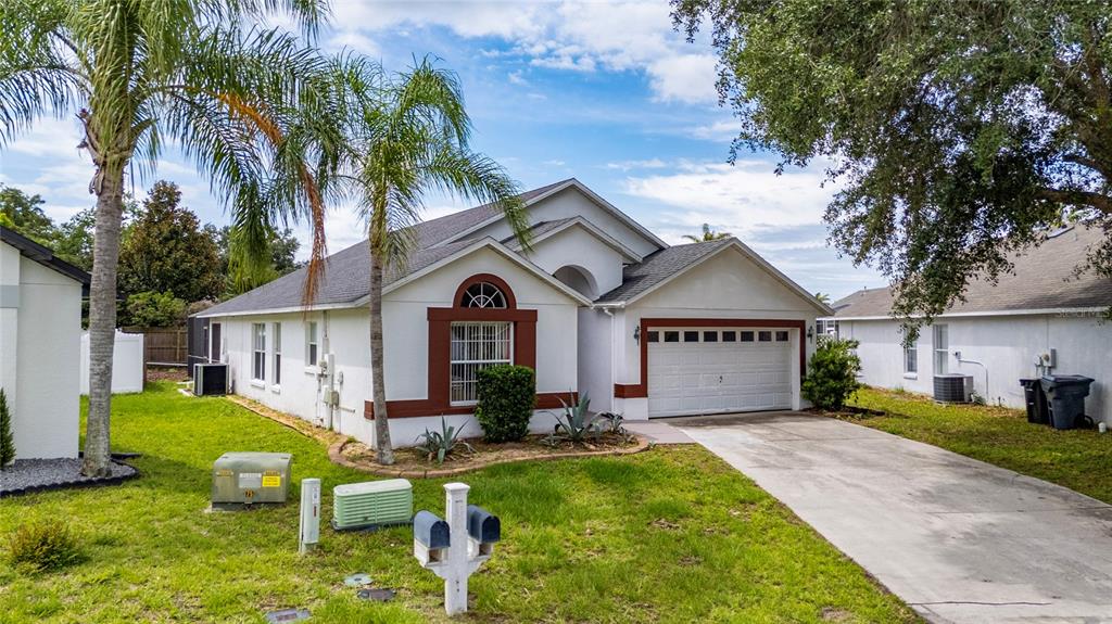 A single-story house with white stucco walls, a brown roof, and a two-car garage — 232 LAKE SHORE PARKWAY, DAVENPORT, FL