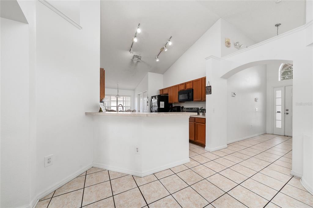 A kitchen with wood cabinets, a breakfast bar, and tile flooring under a vaulted ceiling — 232 LAKE SHORE PARKWAY, DAVENPORT, FL