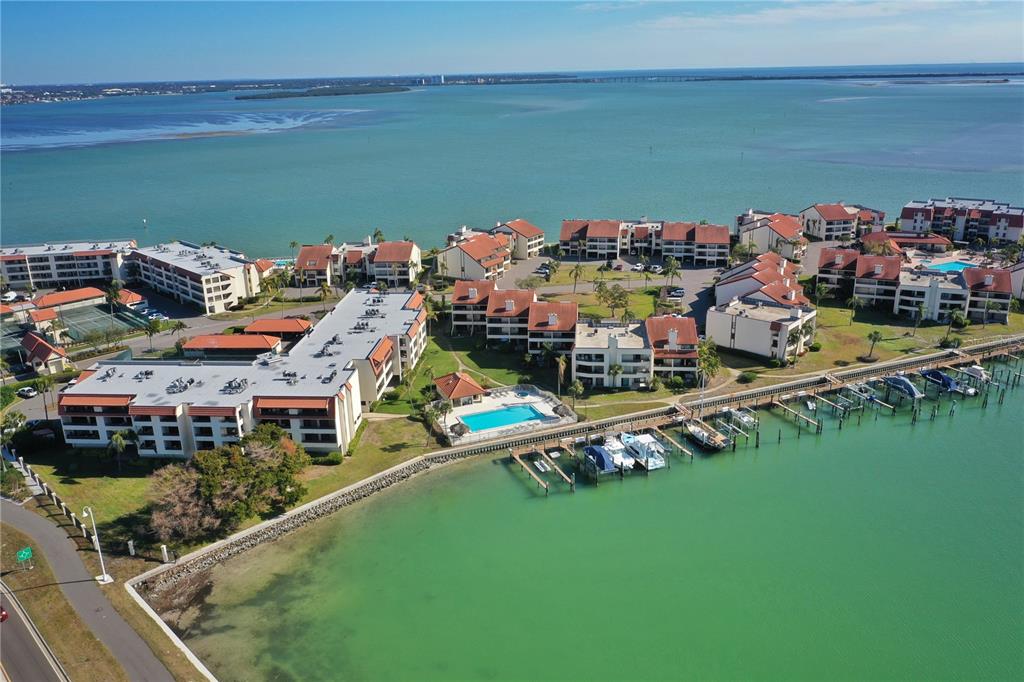 An aerial view shows a waterfront condominium complex with a pool and private boat docks — 106 1ST STREET E UNIT 115, ST PETERSBURG, FL