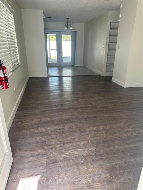 An interior view showing a room with dark wood-look flooring, white walls, and glass doors — 1017 E 1ST AVENUE, MOUNT DORA, FL