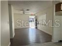An interior view shows a living area with dark wood-look flooring and a ceiling fan — 1017 E 1ST AVENUE, MOUNT DORA, FL