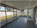 A screened-in porch with a gray concrete floor and a white vinyl privacy fence outside — 1017 E 1ST AVENUE, MOUNT DORA, FL